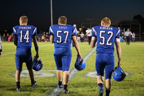 Varsity captains Alex Townsend (14) Matt Teply (57) and Nic Bingham (52) walk out together for the captain's meeting before the home game against Warren.