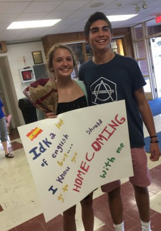 Junior Carlos Herrero shows off his enthusiasm while holding up his date-winning sign with sophomore Sophia Heisler.