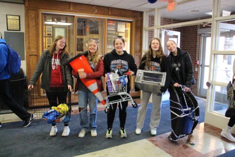 Juniors, Averi Hewitt, Julia Holland, Taylor Burcham, Macy Schulz, and Addison Hefel stand with their backpack substitutes on “Anything but a Backpack Day.” They brought in a dog kennel, a traffic cone, a mini shopping cart, a toaster oven, and a folder trampoline. Many people were impressed with their dedication. “I thought all of the items people brought in were fun and creative,” said Taylor Hilby ‘23. 

