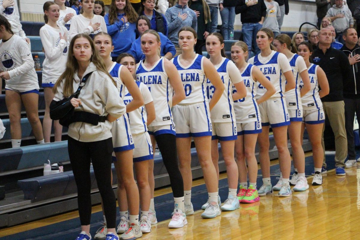 Together united! The girls stand together as the National Anthem plays before the start of their game against Riverdale, a tradition that has been around since 1918. “We didn’t win but were still aggressive, wanting that win when we went to overtime,” said Hulschuer ‘26, “If we could’ve done something differently, we should’ve started the game stronger.” 
